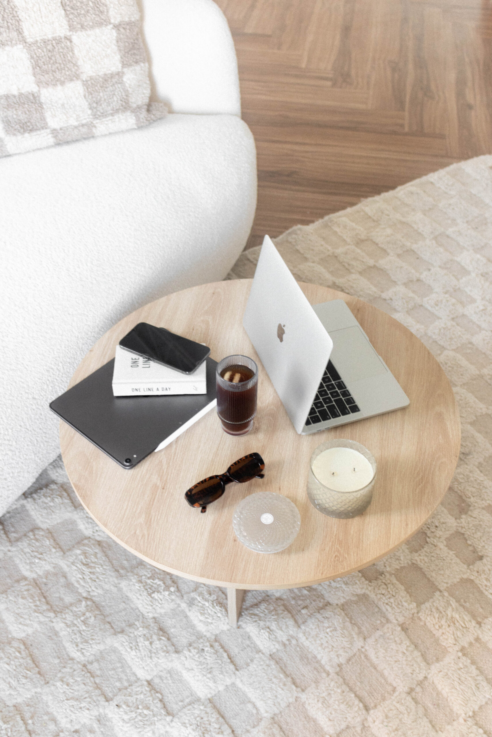 A top down view of a laptop on a table with sunglasses and a drink